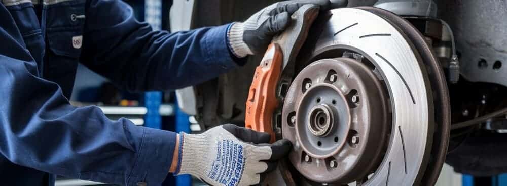 Un mecánico cambiando las pastillas. Esta instalación puede aumentar el precio de las pastillas de freno