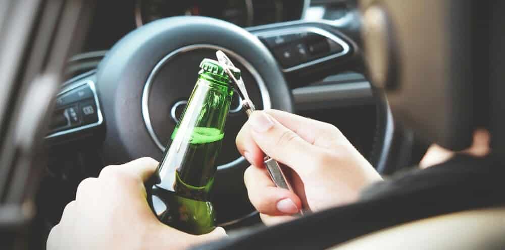 Una persona abriendo un botellín en un coche. Dará positivo en la prueba debido a la tasa de alcohol permitida en 2025