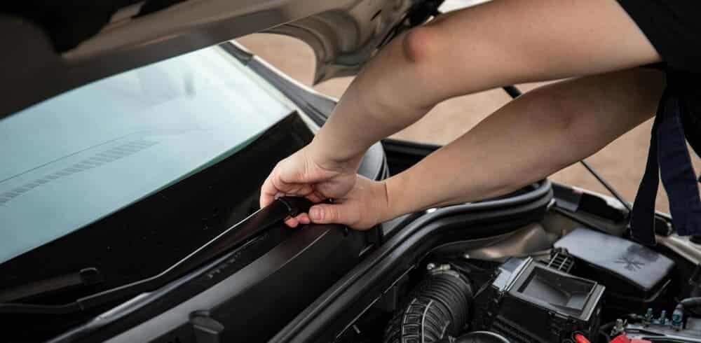 Una persona cambiando las escobillas limpiaparabrisas del coche