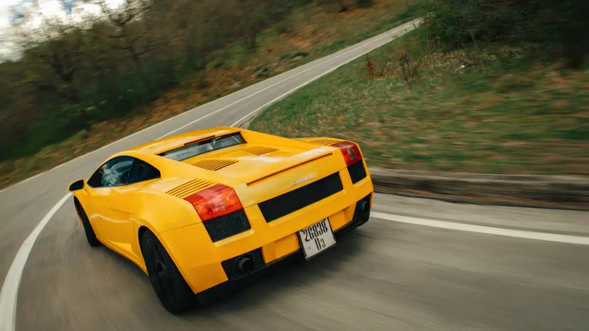 Lamborghini Gallardo amarillo rodando por una carretera de montaña, visto desde atrás