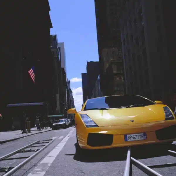 Lamborghini Gallardo coupé amarillo circulando por una calle entre rascacielos, en vista de tres cuartos frontal