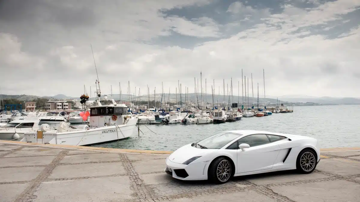 Lamborghini Gallardo Spyder blanco con la capota bajada aparcado junto a un puerto deportivo