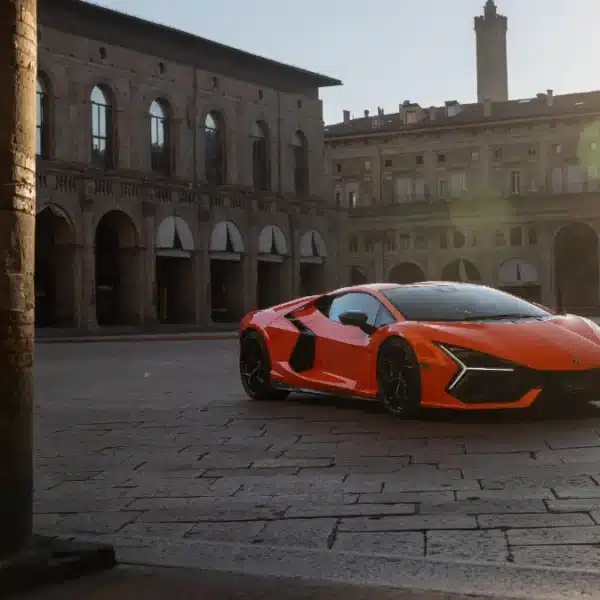 Lamborghini Revuelto naranja aparcado frente a un palacio histórico de Bolonia al atardecer