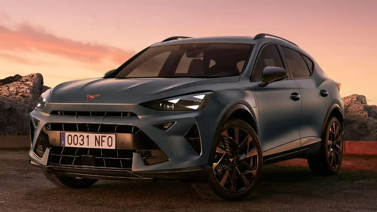 Un SUV deportivo Cupra Formentor de color azul mate estacionado en un paisaje rocoso al atardecer.