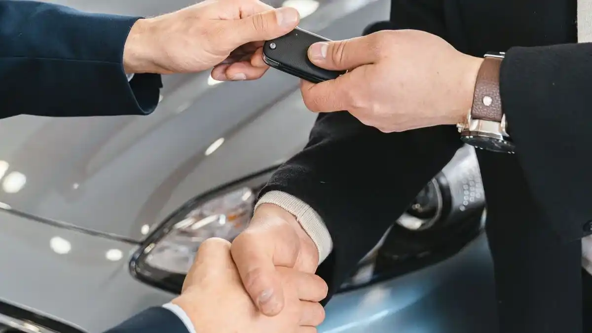 Dos personas llegando a un acuerdo entregando las llaves de un coche de renting o alquiler a largo plazo