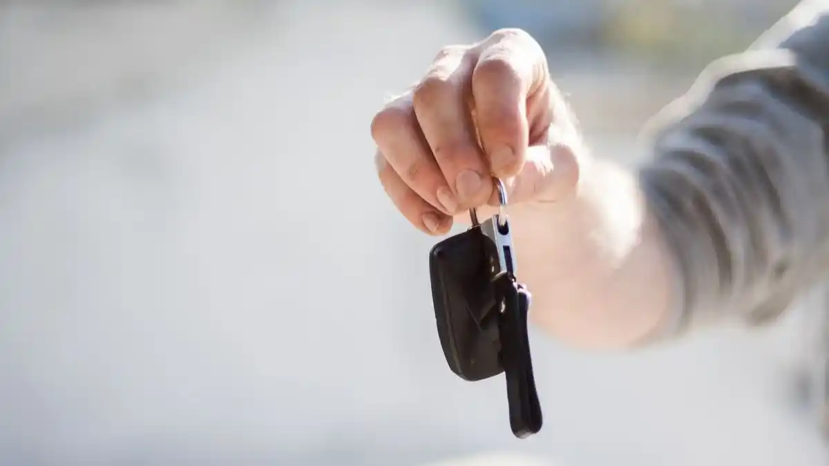 Una persona con unas llaves de un coche de alquiler a largo plazo o renting