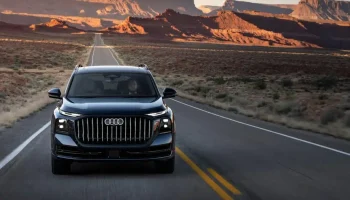 Audi Q9 circulando por una carretera desértica al atardecer